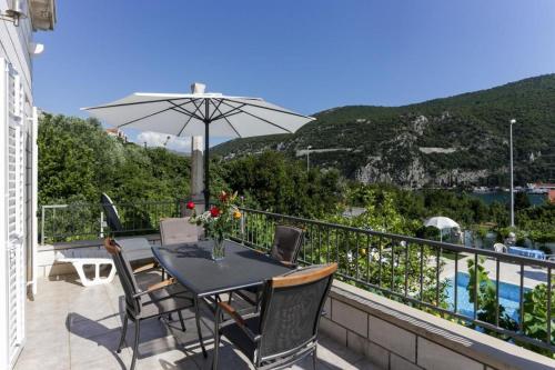 una mesa y sillas en un balcón con sombrilla en Villa Celenca, en Mokošica