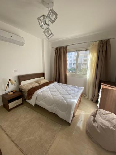 Un dormitorio con una cama grande y una ventana en Madinaty Well-furnished 3- Bedroom apartment - شقة فندقيه للايجار مدينتي en Madīnat ash Shurūq