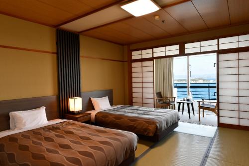 a hotel room with two beds and a balcony at The Gran Resort Elegante Shirahama in Shirahama