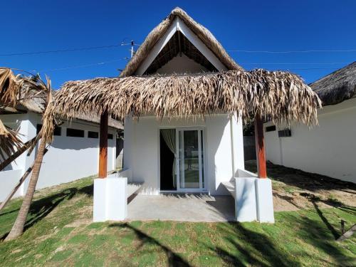 a small white house with a thatched roof at Ikani Surf Resort in Pagudpud