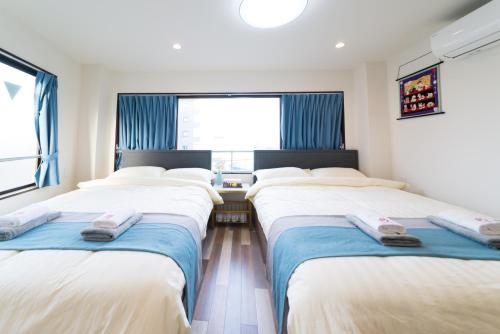 a row of beds in a room with a window at High Five Guest House in Tokyo