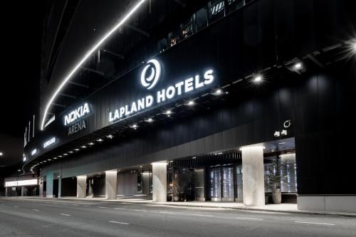 a building with a sign on the side of it at night at Lapland Hotels Arena in Tampere