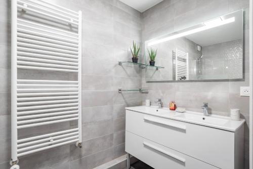 La salle de bains blanche est pourvue d'un lavabo et d'un miroir. dans l'établissement L'Académie - GOLDEN TREE - Parking Privé & Wifi - 5 min centre ville de Strasbourg, à Strasbourg