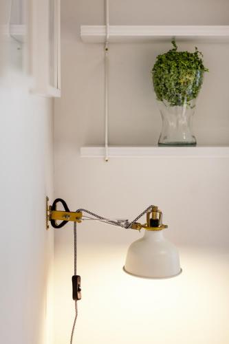 a lamp on a wall with a vase on a shelf at Apartamenty Black&White in Gdynia