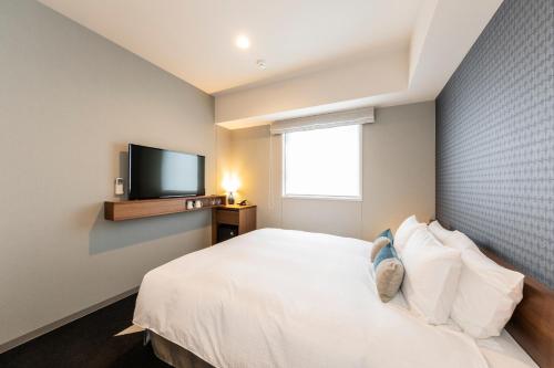 a bedroom with a white bed and a flat screen tv at Tokyu Stay Sapporo Odori in Sapporo