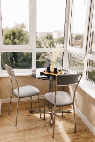 a table and chairs in a room with windows at NUDE Просторі апартаменти біля історичного центру вул.Збаразька in Ternopilʼ