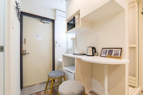 una pequeña cocina con encimera y taburete en High Five Guest House, en Tokio