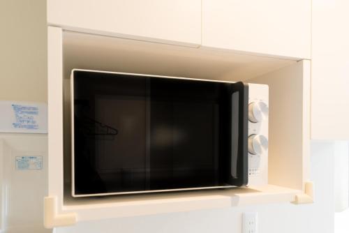 a microwave oven that is on a wall at High Five Guest House in Tokyo
