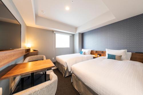 a hotel room with two beds and a flat screen tv at Tokyu Stay Sapporo Odori in Sapporo