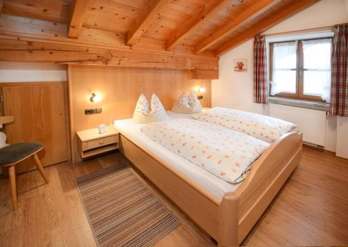 ein Schlafzimmer mit einem großen Bett und einer Holzdecke in der Unterkunft Dammerer Hof in Ruhpolding