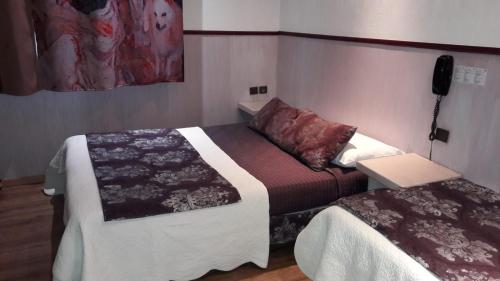 a small room with two beds and a phone at Hotel Mignon in Avignon