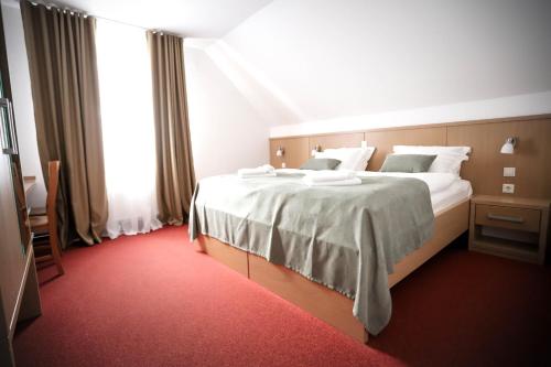 a bedroom with a large bed with white sheets at Hotel Pino Alpino in Kranjska Gora