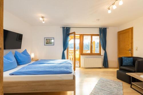 a bedroom with a bed with blue sheets and a couch at Apartment-mit-Balkon in Hergensweiler