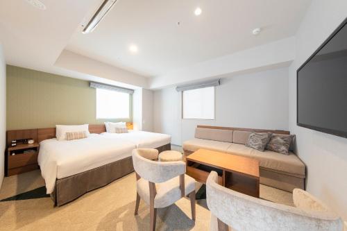 a bedroom with a bed and a couch and a tv at Tokyu Stay Sapporo Odori in Sapporo