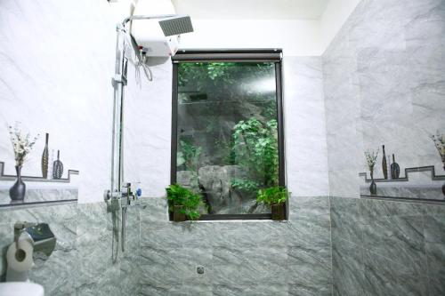 a bathroom with a shower with a window with plants at Tam Coc Valley Homestay in Ninh Binh