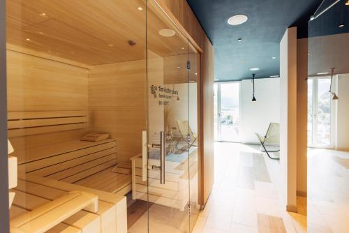 a sauna with wooden walls and a glass wall at harry's home Bischofshofen hotel & apartments in Bischofshofen