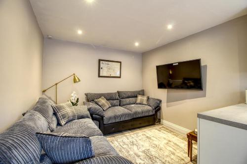 a living room with a couch and a flat screen tv at 6 Dbl Bed, Central Huddersfield house inc parking in Huddersfield