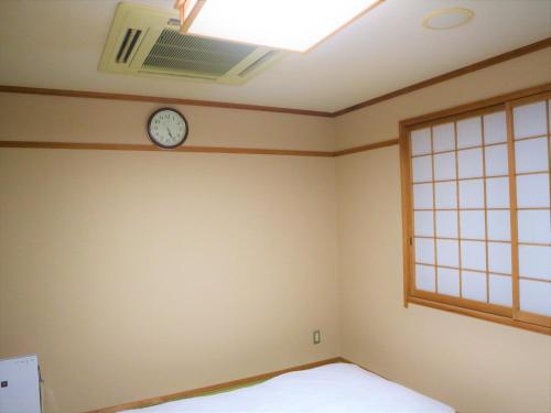 a bedroom with a clock on the wall and a window at Bayside Hotel Ryugu / Vacation STAY 63718 in Anan