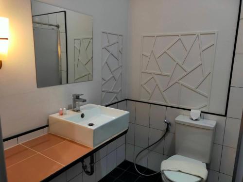 a bathroom with a sink and a toilet and a mirror at TaamJai Resort in Nakhon Phanom
