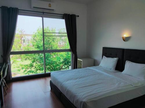 a bedroom with a bed and a large window at TaamJai Resort in Nakhon Phanom