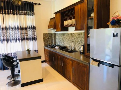 Mirissa Paddy House في ميريسا: مطبخ مع ثلاجة بيضاء ودواليب خشبية