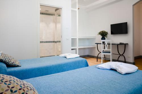 a room with two beds with blue sheets and a television at Le Dune Sicily Hotel in Catania