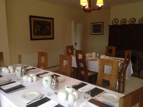 a dining room with a table with white plates and glasses at Whitethorn Bed and Breakfast in Congleton