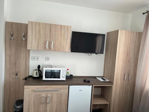 a kitchen with wooden cabinets and a microwave at Penzion Na Rozcestí in Bulhary