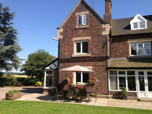 a brick house with chairs and an umbrella at Whitethorn Bed and Breakfast in Congleton