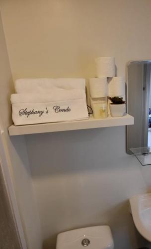 a shelf in a bathroom with towels and a toilet at Steff's CONDO 1016 at CENTRIO Tower in Cagayan de Oro