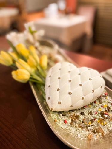 a heart shaped cake on a tray with flowers at City Hotel Ost am Kö in Augsburg