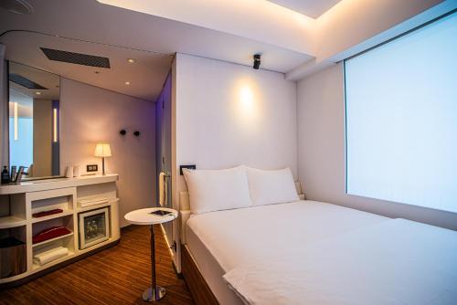 a small bedroom with a bed and a mirror at citizenM Taipei North Gate in Taipei