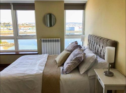 ein Schlafzimmer mit einem großen Bett mit Kissen darauf in der Unterkunft Graña Beach Ferrol in A Coruña
