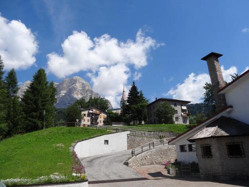 a house on a hill with a mountain in the background at HG Hotel La Caminatha in Val di Zoldo