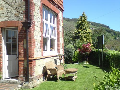 a house with a chair and a table in the yard at Cornerways in Ventnor