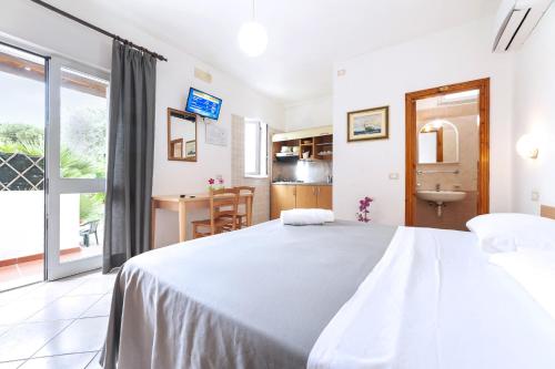 a bedroom with a large white bed and a kitchen at Casa Cigliano in Ischia