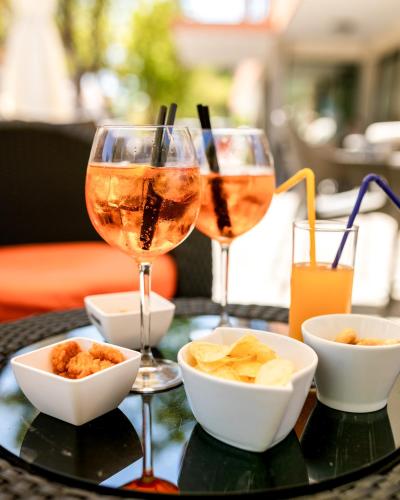 two glasses of wine and bowls of food on a table at Hotel Apollo in Cesenatico