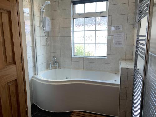 uma banheira branca na casa de banho com uma janela em The Cottage At The Retreat em Leek