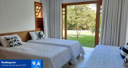 a hotel room with two beds and a window at PRAIA DO FORTE - PISCINAS NATURAIS in Praia do Forte