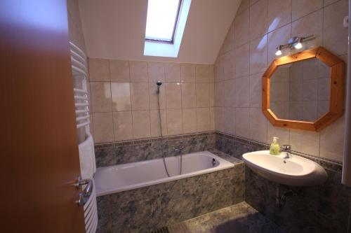 a bathroom with a sink and a bath tub and a mirror at Mandula Wellness Apartmanház in Harkány