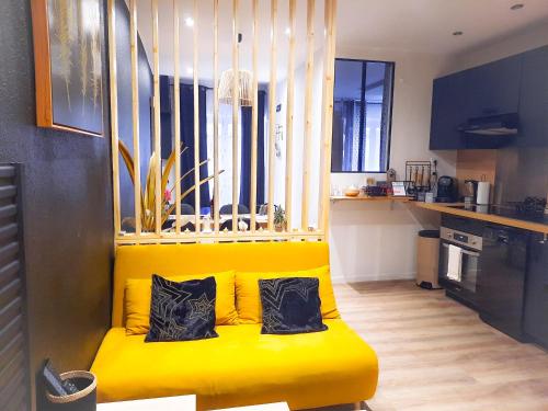 a yellow couch in a kitchen with two pillows on it at Orion in Clermont-Ferrand