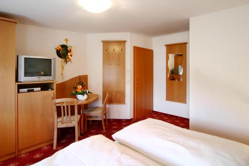a bedroom with a bed and a table and a television at Hotel Traunfall in Viecht
