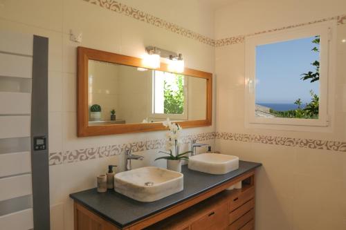 een badkamer met twee wastafels en een spiegel bij Villa Marine en bord de mer... in Lumio