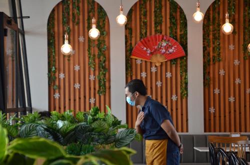 a man wearing a mask in a restaurant with an umbrella at Kala Hotel Semarang in Jomblang