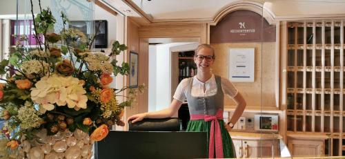 una mujer parada frente a una exposición de flores en Hotel Neuhintertux en Tux