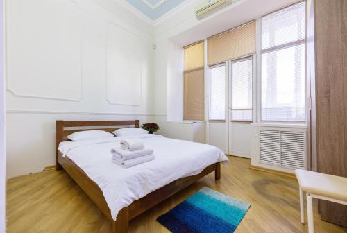 a bedroom with a bed with white sheets and windows at Квартира в центре Киева in Kyiv