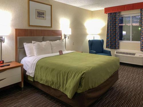 a hotel room with a large bed and a blue chair at Quality Inn near Toms River Corporate Park in Manchester Township