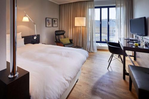 a hotel room with a large bed and a desk and chair at Parkhotel Pforzheim in Pforzheim