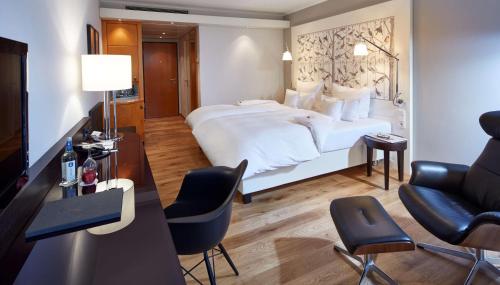 a hotel room with a large bed and chairs at Parkhotel Pforzheim in Pforzheim