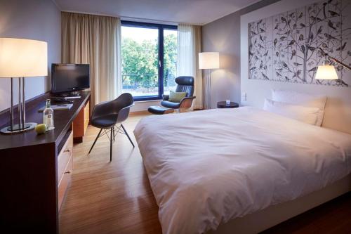 a hotel room with a large bed and a television at Parkhotel Pforzheim in Pforzheim